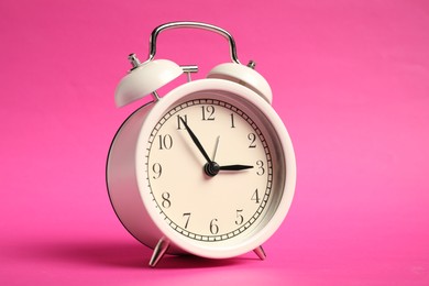 Photo of One white alarm clock on bright pink background