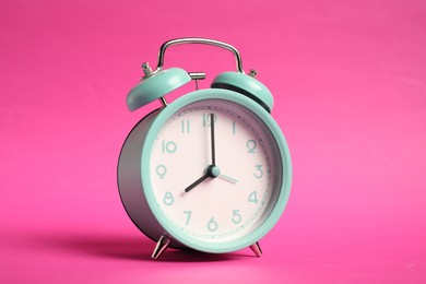 Photo of One turquoise alarm clock on bright pink background