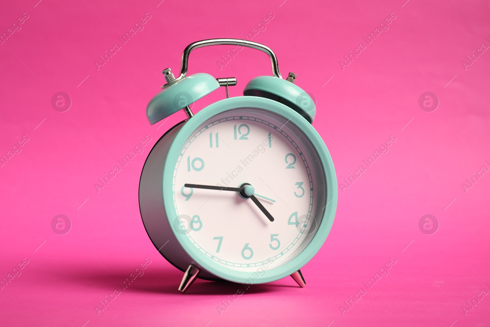 Photo of One turquoise alarm clock on bright pink background