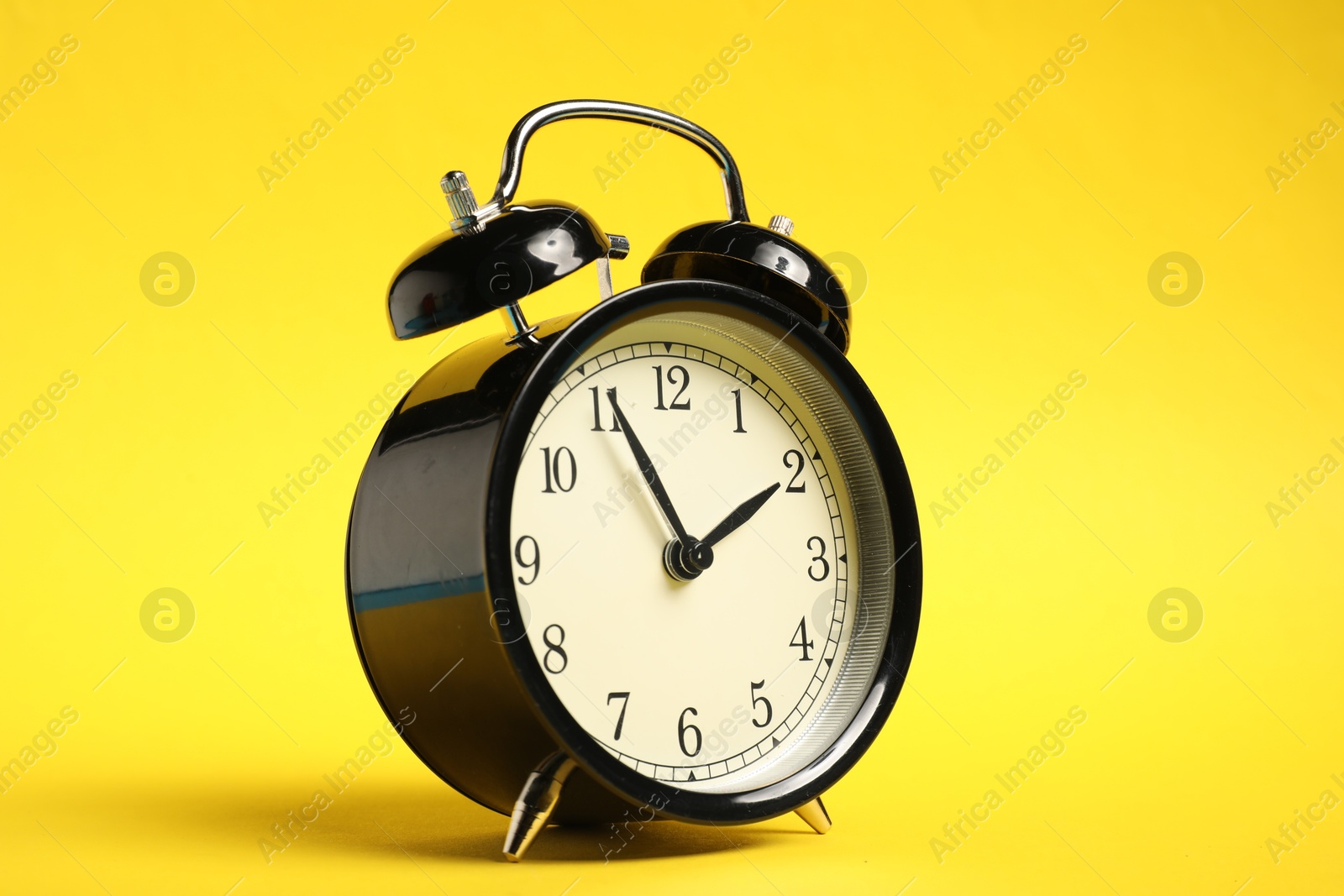 Photo of One black alarm clock on yellow background