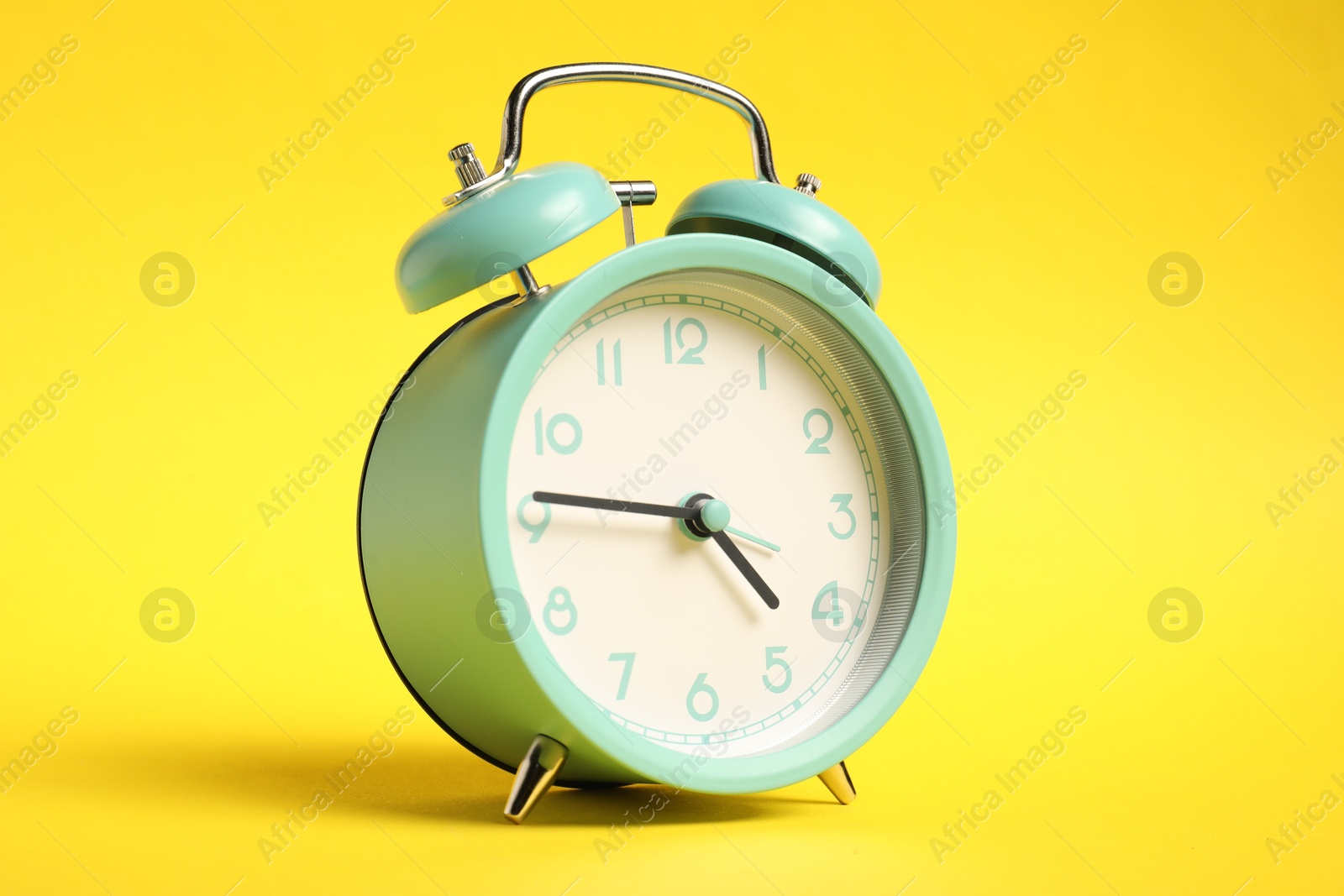 Photo of One turquoise alarm clock on yellow background