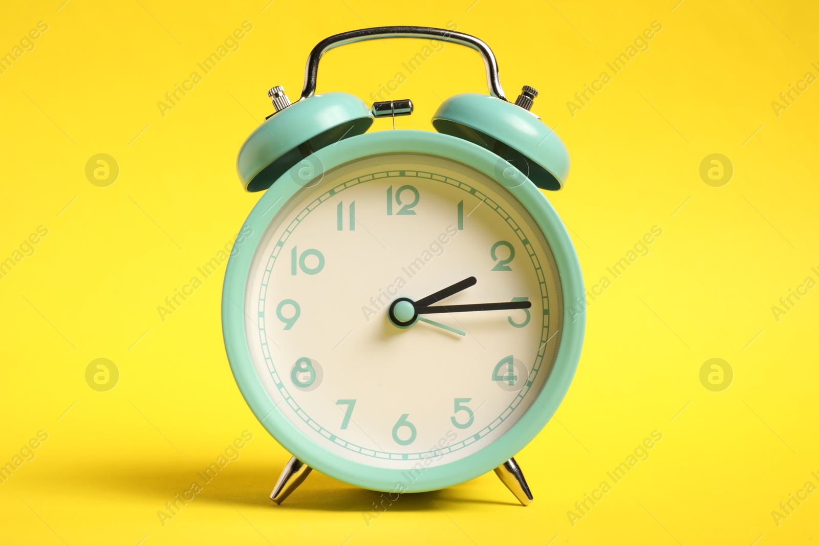 Photo of One turquoise alarm clock on yellow background