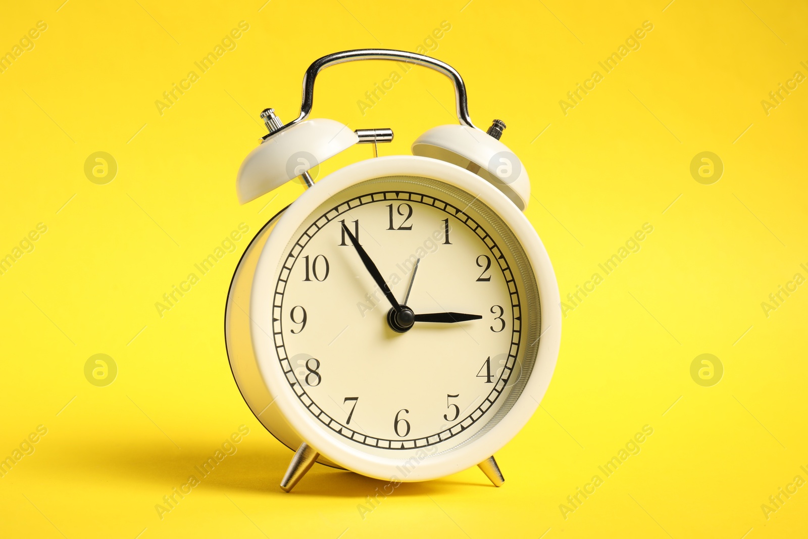 Photo of One white alarm clock on yellow background