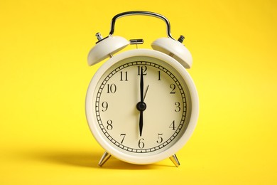 Photo of One white alarm clock on yellow background