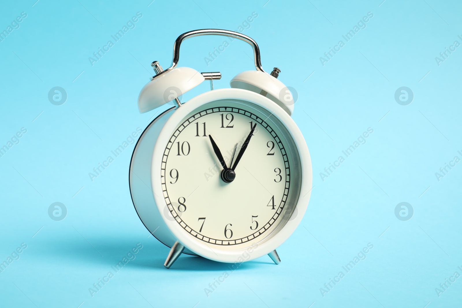 Photo of One white alarm clock on light blue background