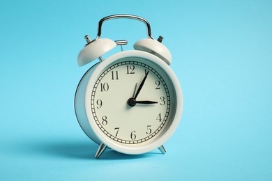 Photo of One white alarm clock on light blue background