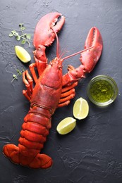 Photo of Delicious boiled lobster with lime pieces, oil and microgreens on black table, flat lay