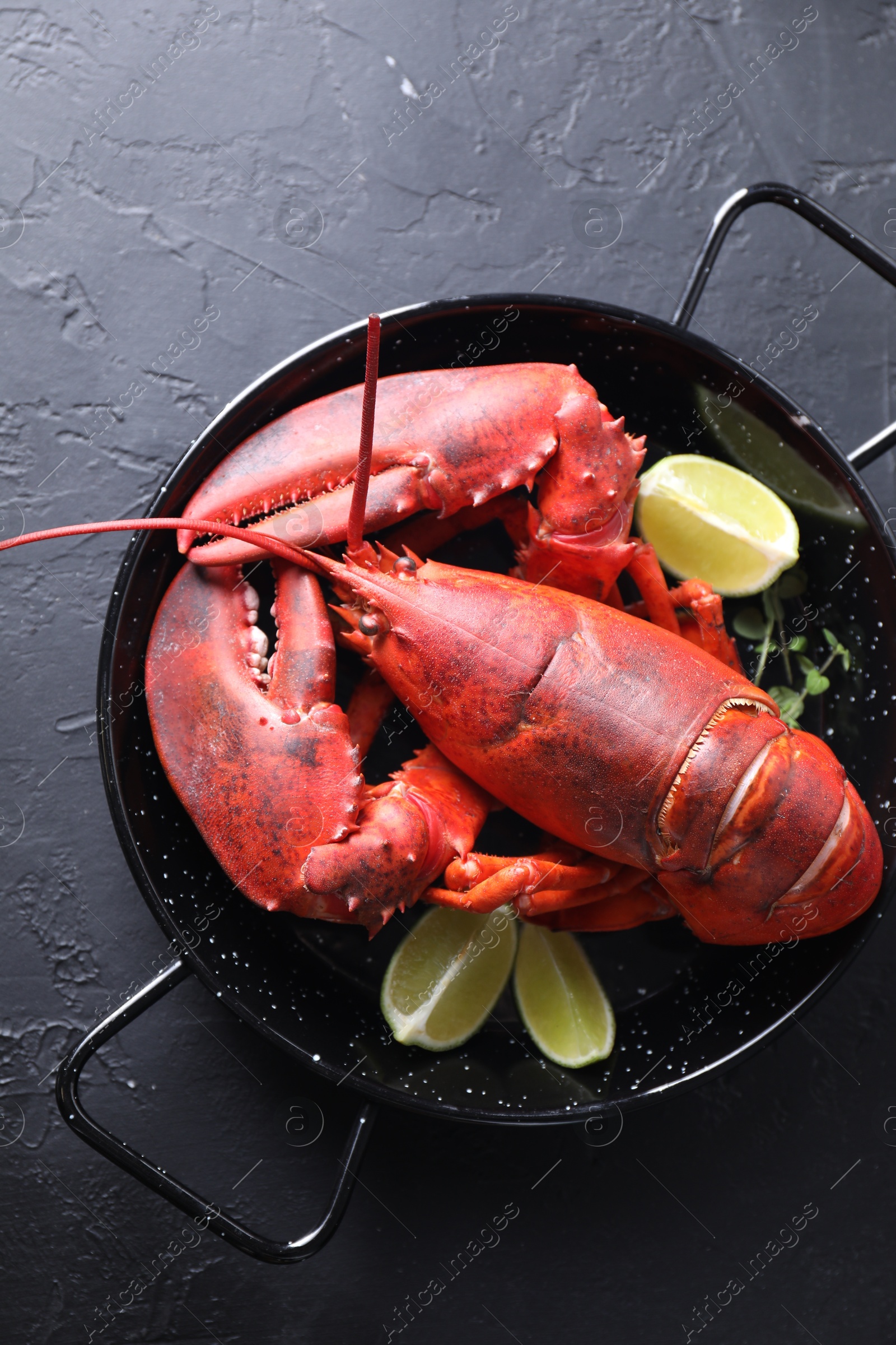 Photo of Delicious boiled lobster with lime pieces and microgreens on black table, top view