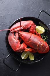 Photo of Delicious boiled lobster with lime pieces and microgreens on black table, top view