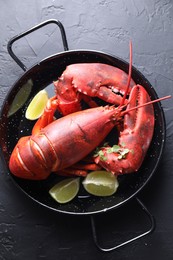 Photo of Delicious boiled lobster with lime pieces and microgreens on black table, top view