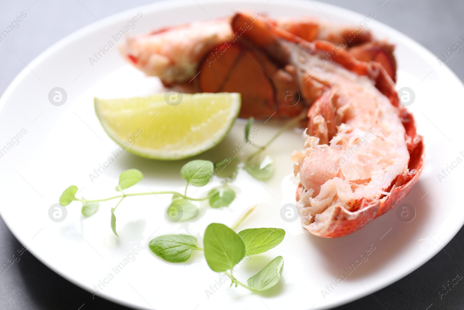 Photo of Delicious tail of boiled lobster served on grey table, closeup