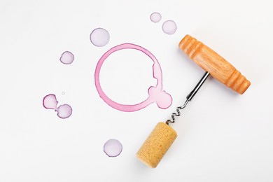 Photo of Corkscrew, cork and red wine stains on white background, top view