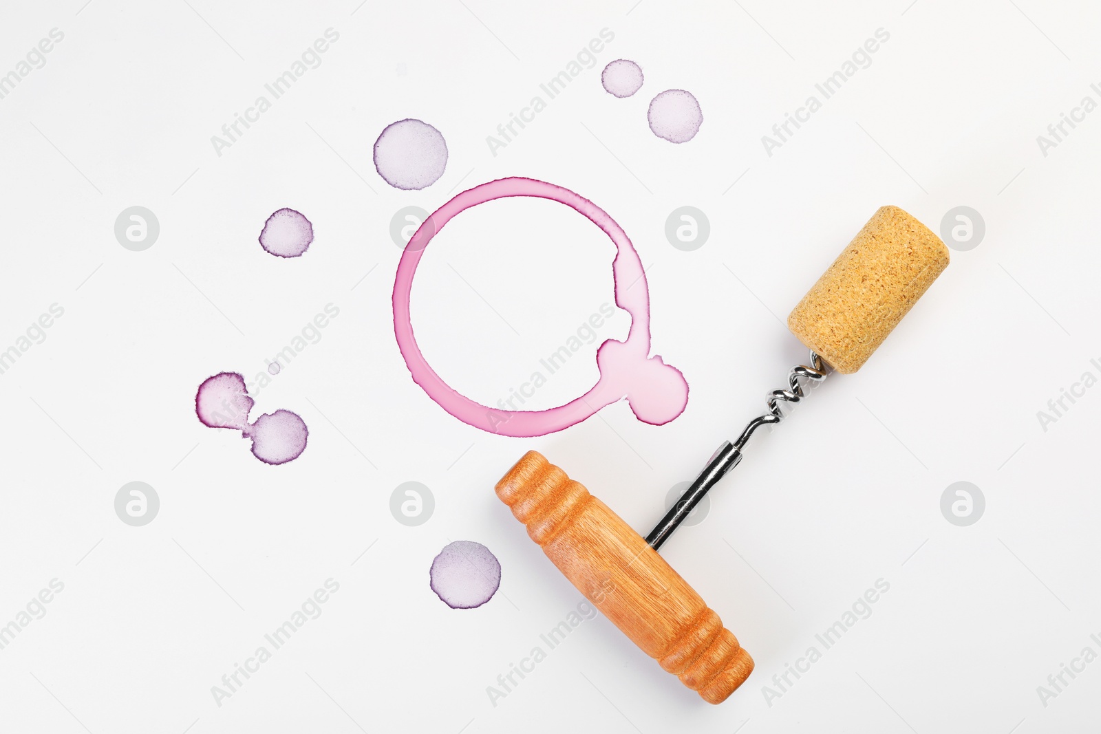 Photo of Corkscrew, cork and red wine stains on white background, top view