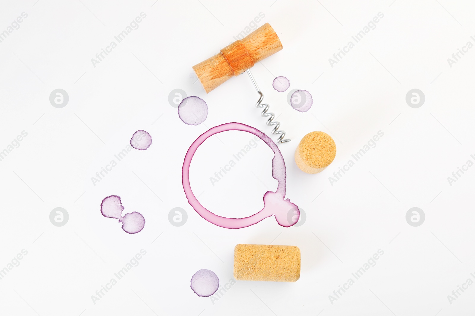 Photo of Corkscrew, corks and red wine stains on white background, top view