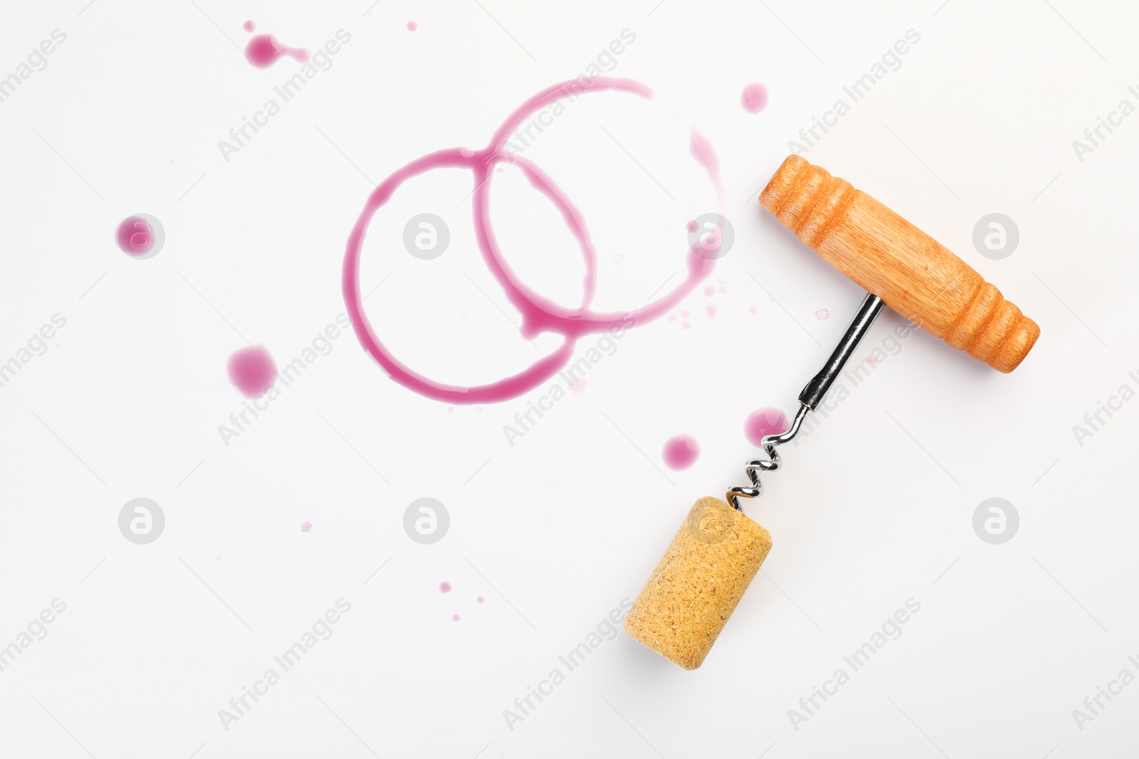 Photo of Corkscrew, cork and red wine stains on white background, top view