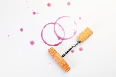 Photo of Corkscrew, cork and red wine stains on white background, top view