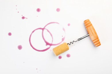 Photo of Corkscrew, cork and red wine stains on white background, top view