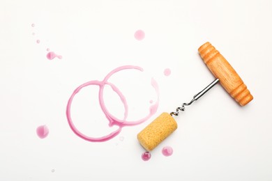 Photo of Corkscrew, cork and red wine stains on white background, top view