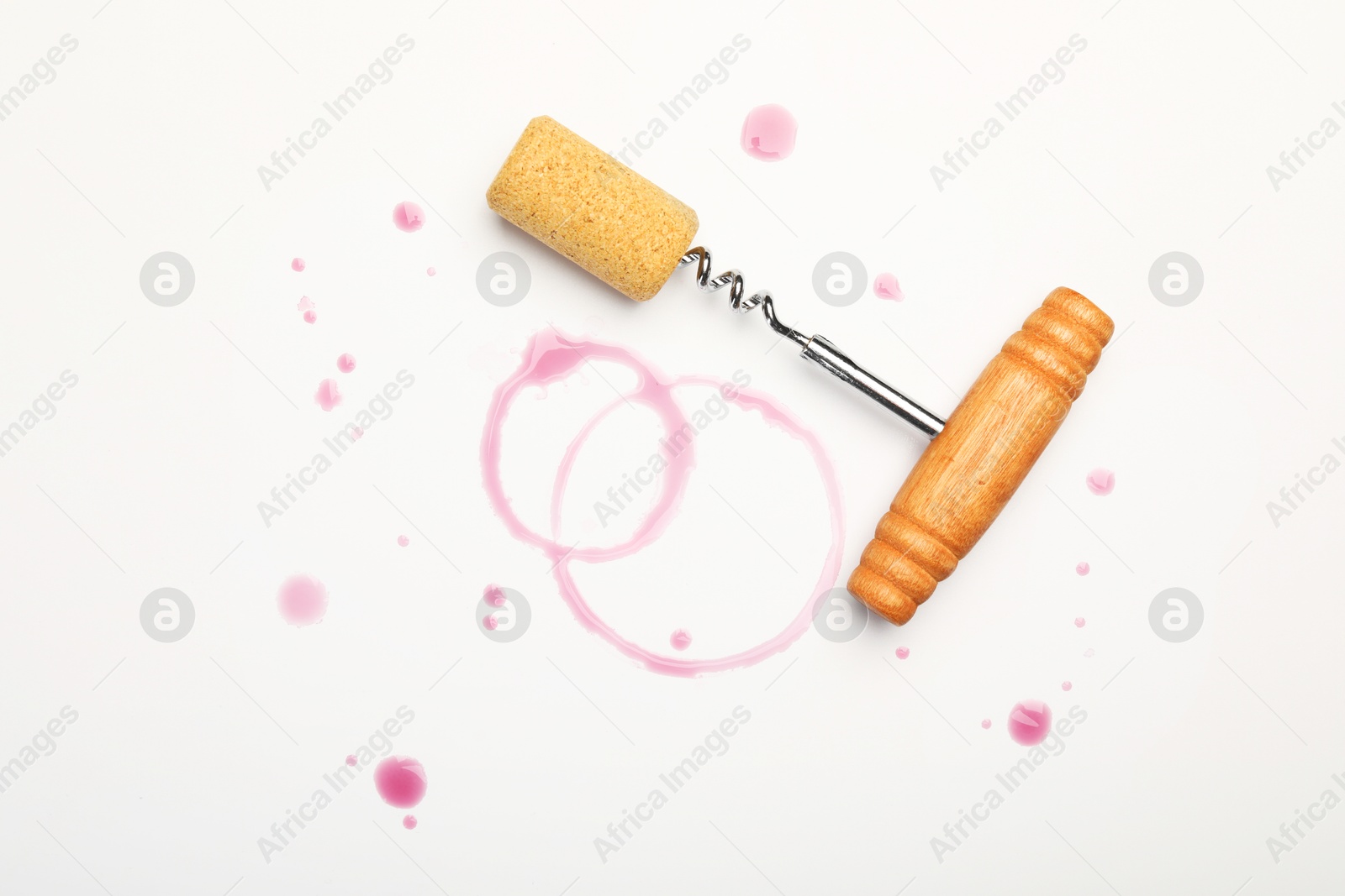 Photo of Corkscrew, cork and red wine stains on white background, top view