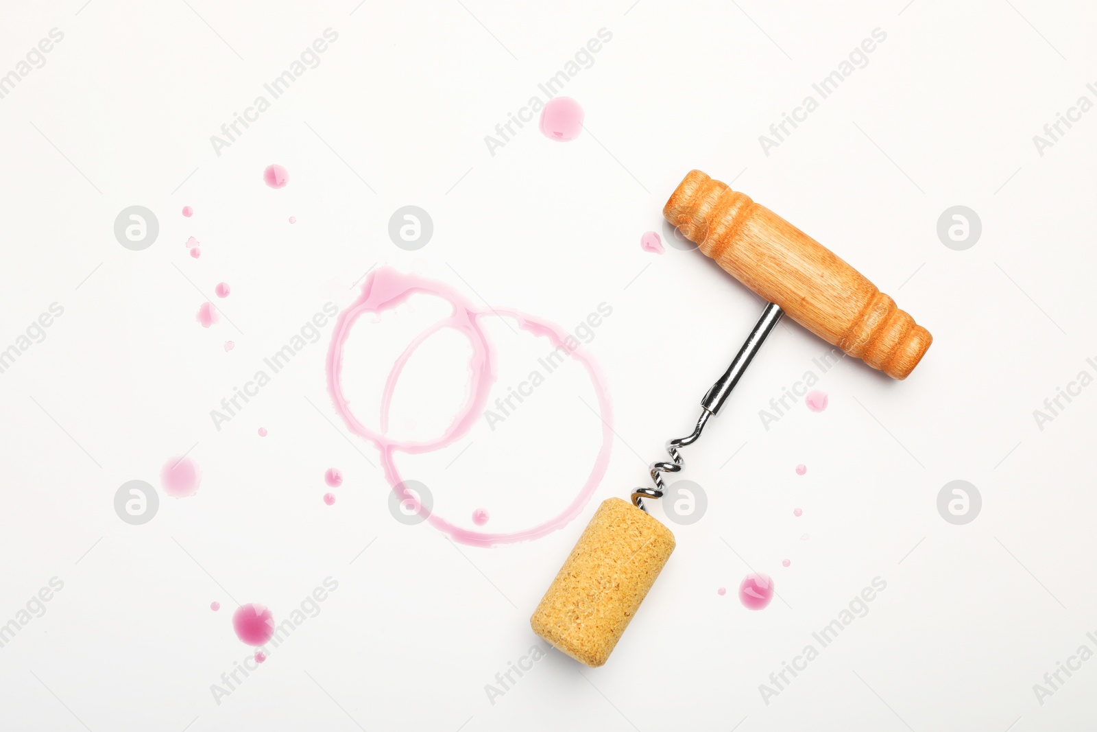 Photo of Corkscrew, cork and red wine stains on white background, top view