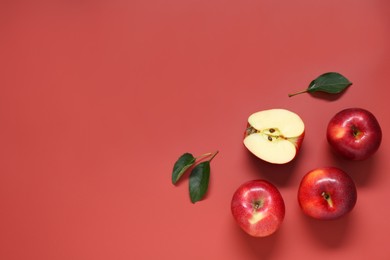 Photo of Fresh apples and green leaves on red background, flat lay. Space for text