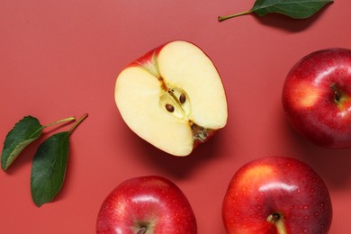 Photo of Fresh apples and green leaves on red background, flat lay