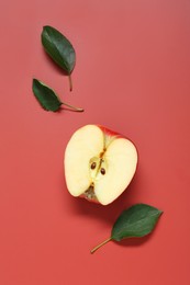 Photo of Half of apple and leaves on red background, flat lay