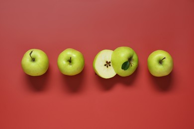 Photo of Whole and cut apples on red background, flat lay