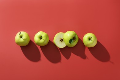 Photo of Whole and cut apples on red background, flat lay