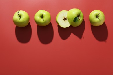 Photo of Whole and cut apples on red background, flat lay. Space for text