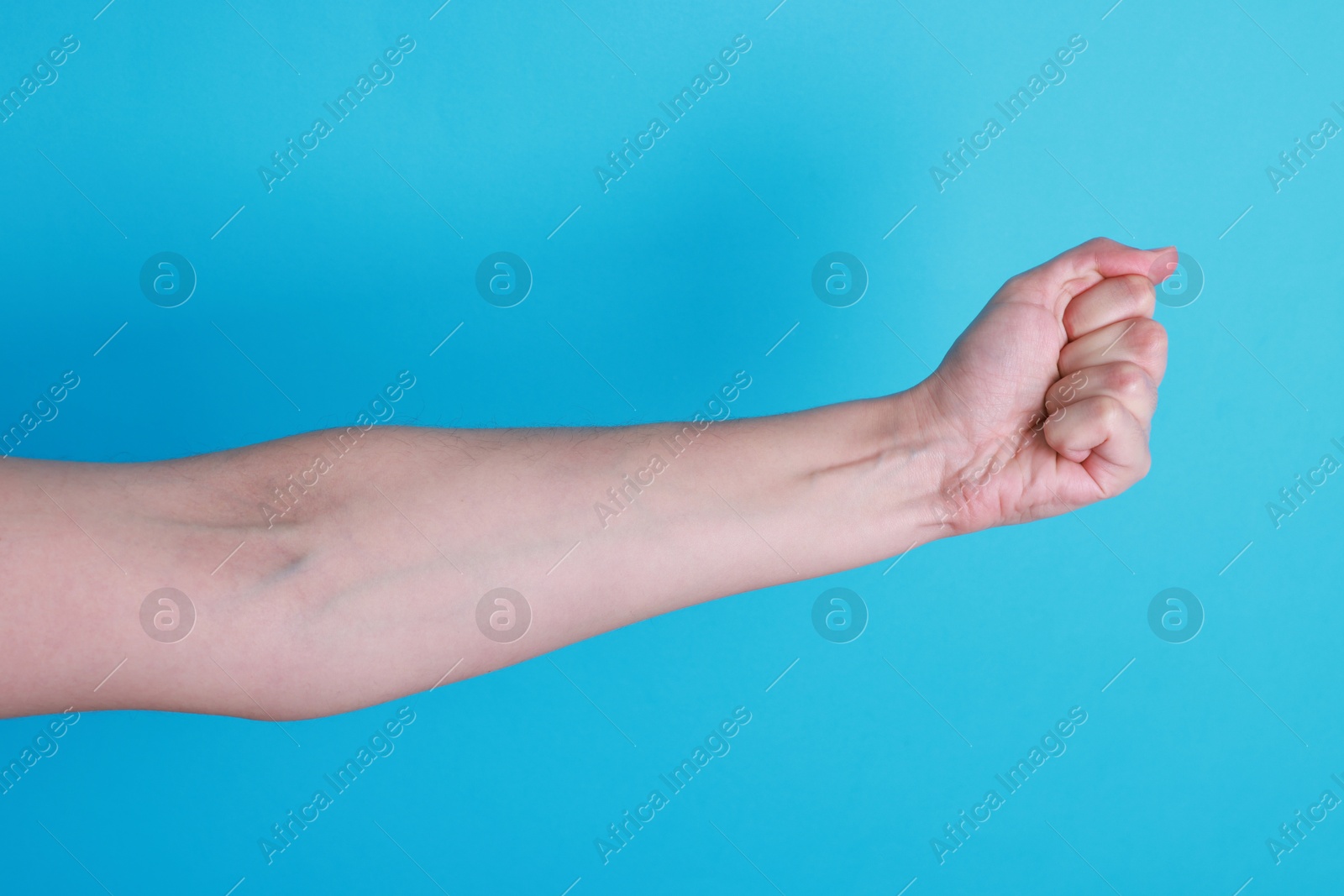 Photo of Woman with visible hand veins on light blue background, closeup