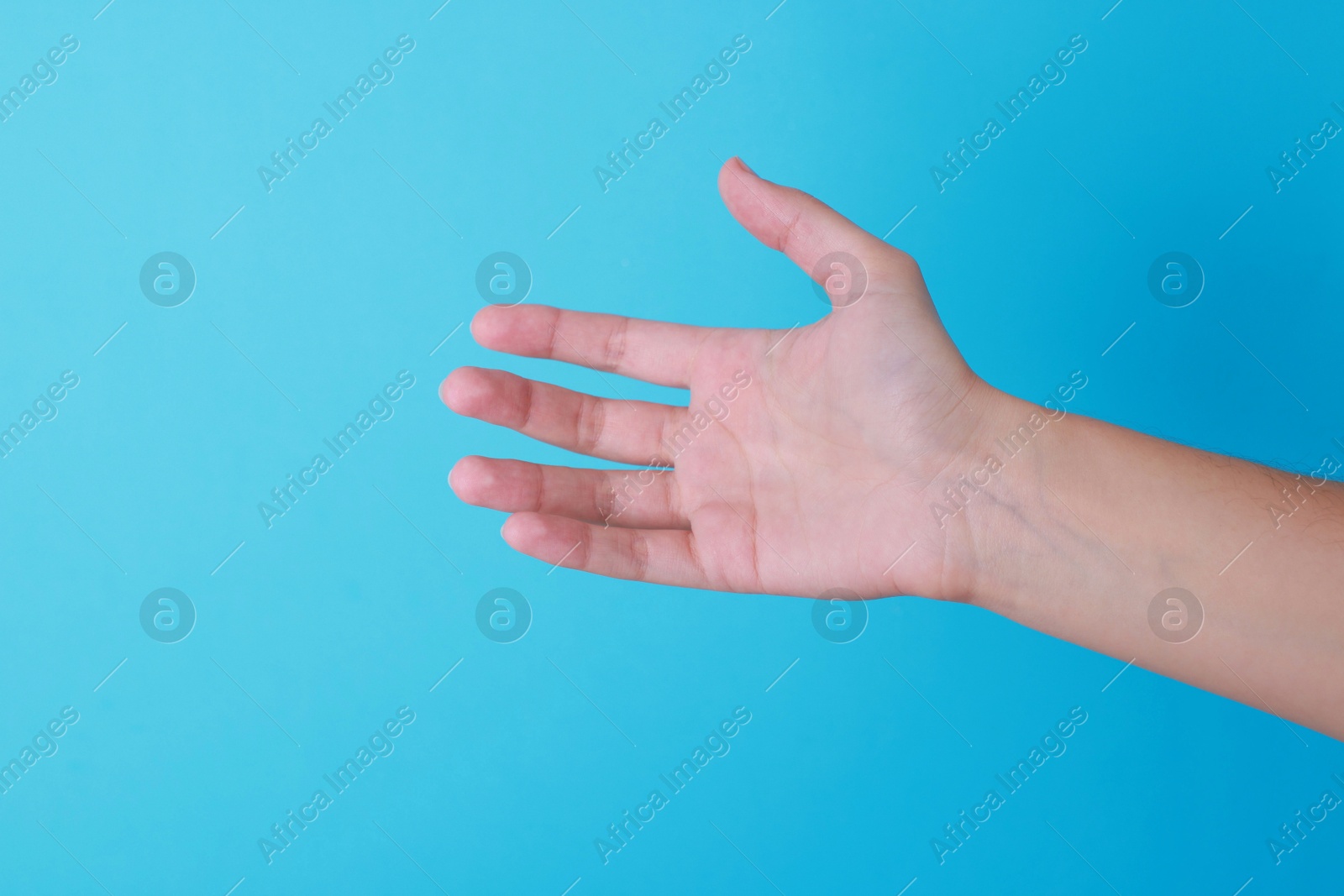 Photo of Woman with visible hand veins on light blue background, closeup