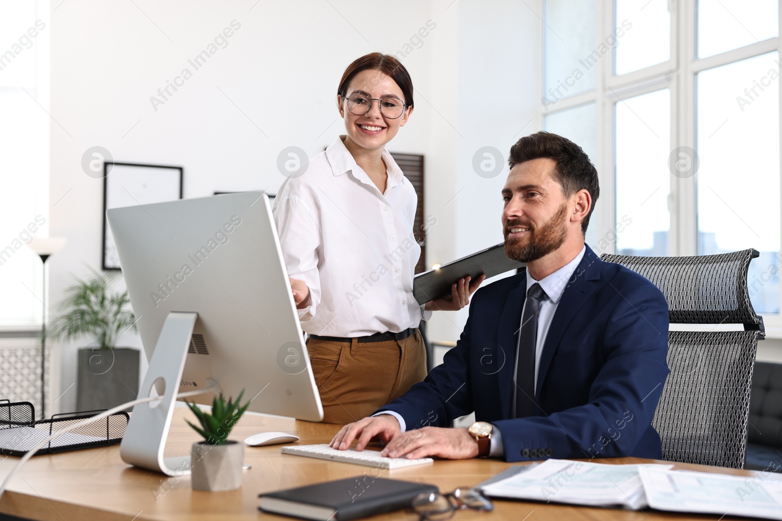 Photo of Colleagues working with computer at desk in office