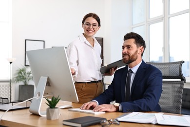 Photo of Colleagues working with computer at desk in office