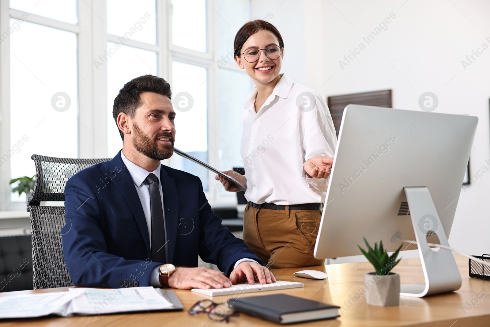 Photo of Colleagues working with computer at desk in office