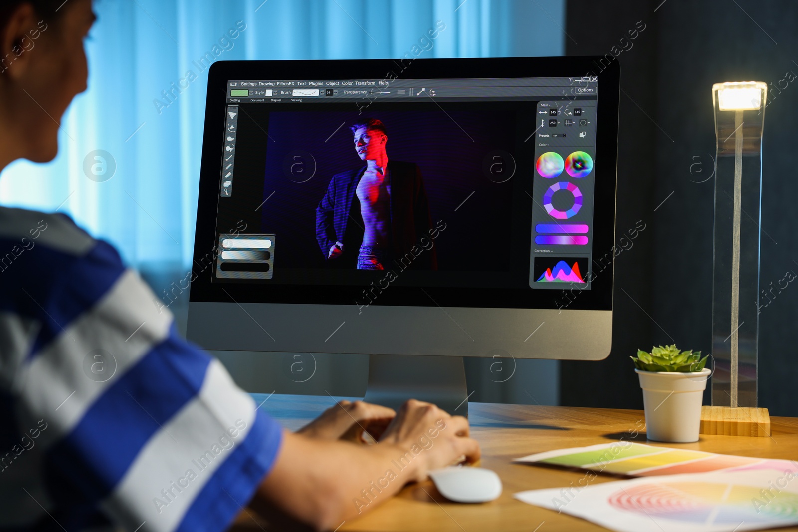 Photo of Designer working on computer indoors at night, closeup