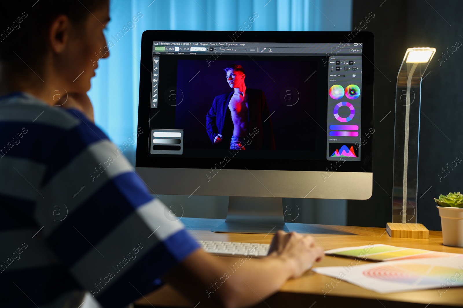 Photo of Designer working on computer indoors at night, closeup