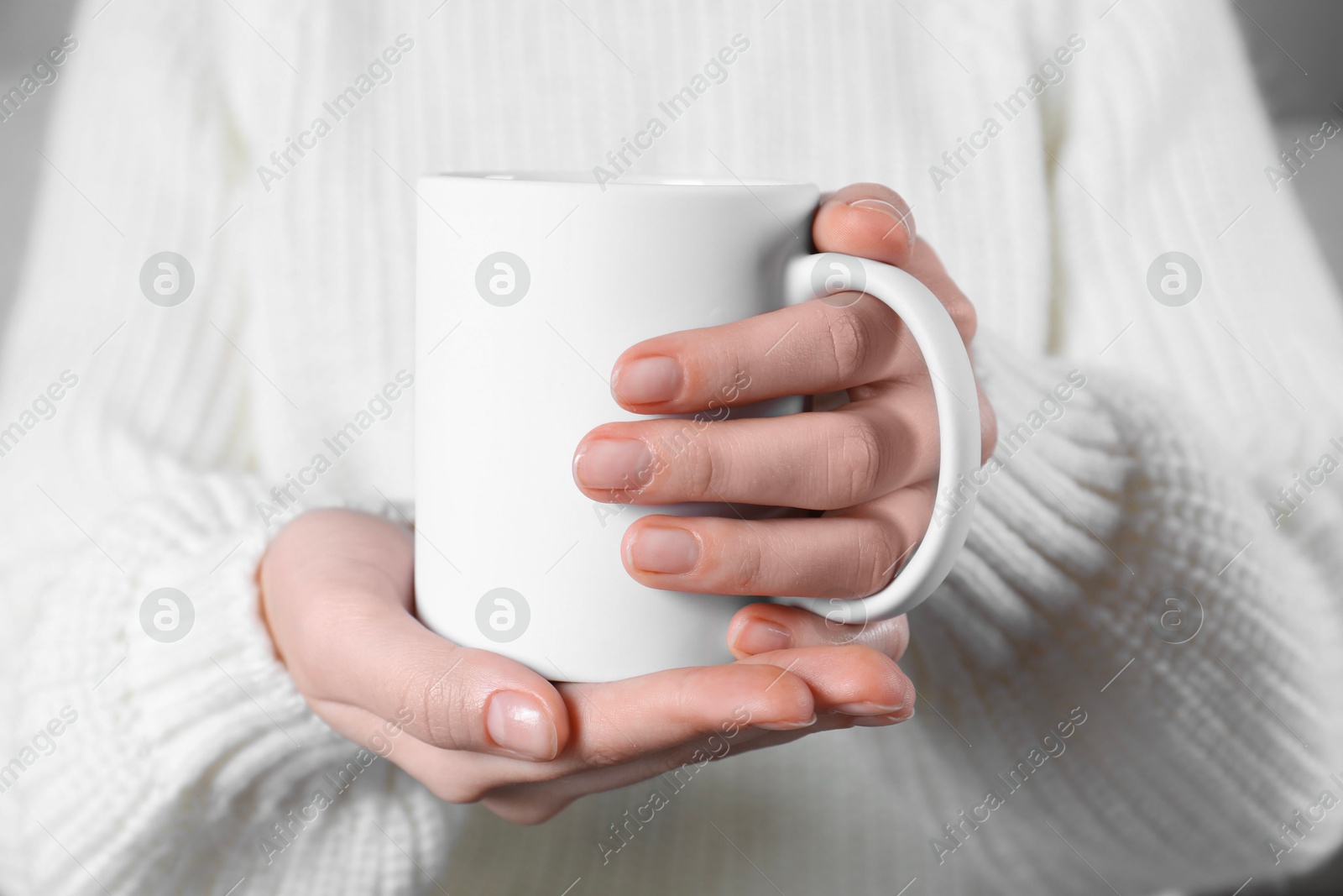 Photo of Woman holding blank white ceramic mug, closeup. Mockup for design