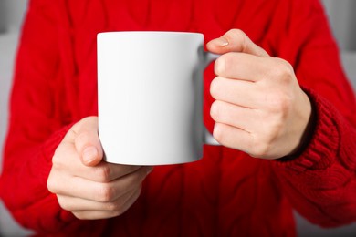 Photo of Woman holding blank white ceramic mug, closeup. Mockup for design