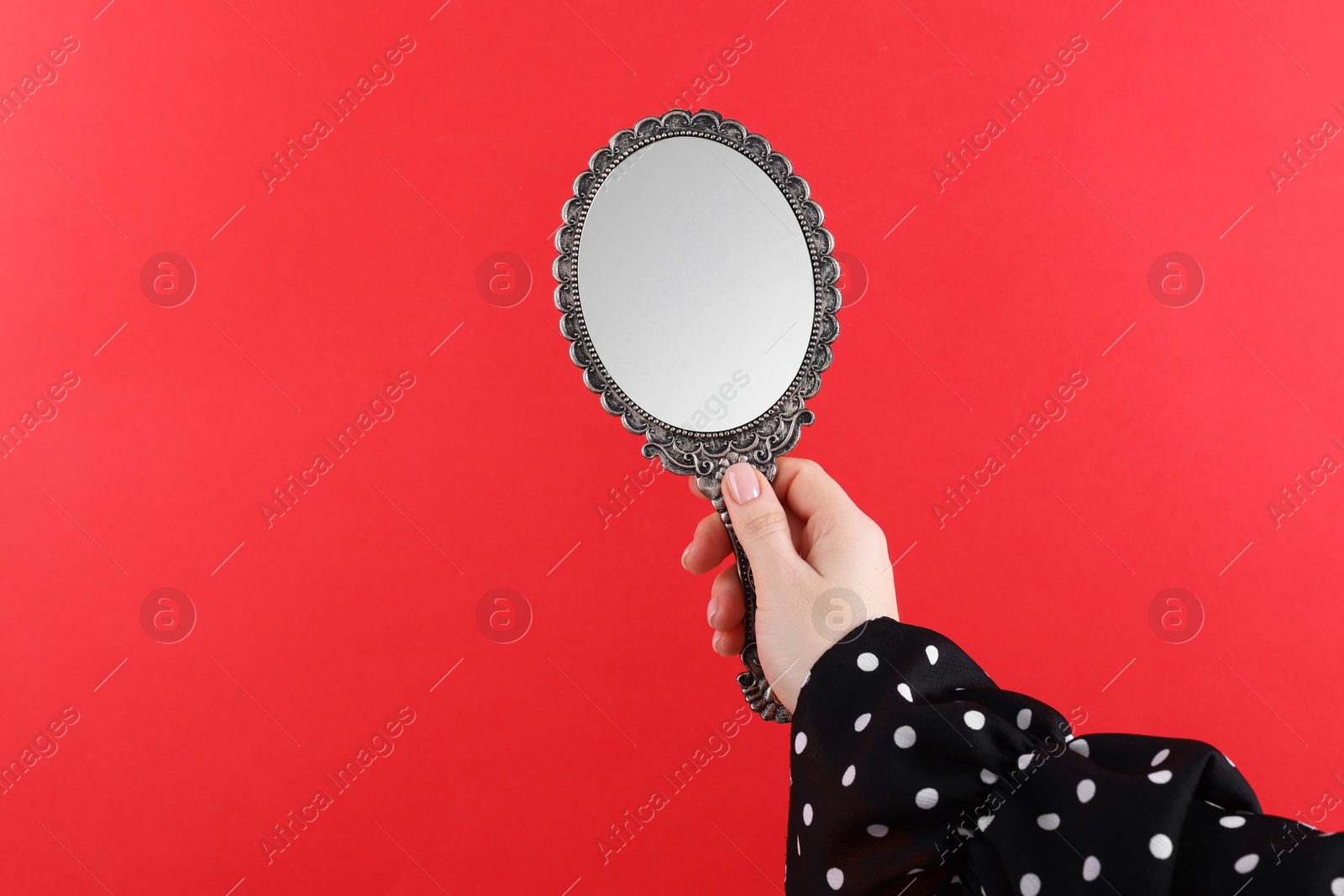 Photo of Woman holding beautiful mirror on red background, closeup. Space for text