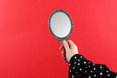 Photo of Woman holding beautiful mirror on red background, closeup. Space for text