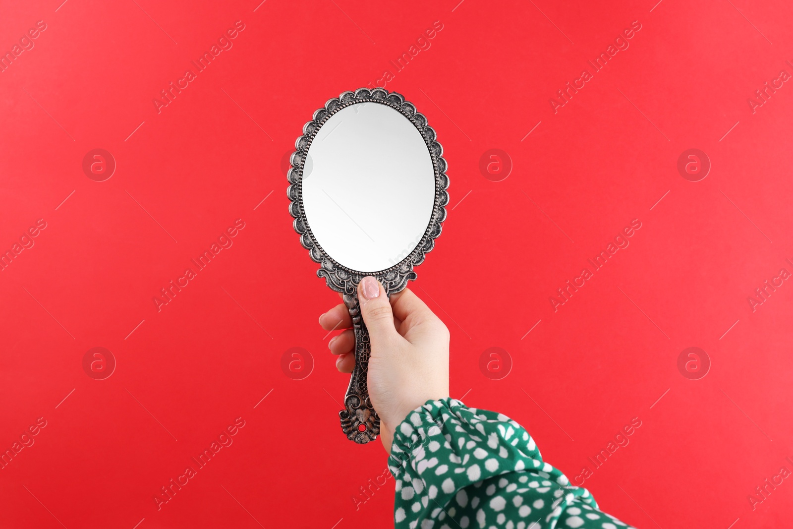 Photo of Woman holding beautiful mirror on red background, closeup