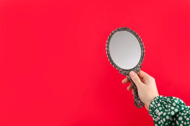 Photo of Woman holding beautiful mirror on red background, closeup. Space for text