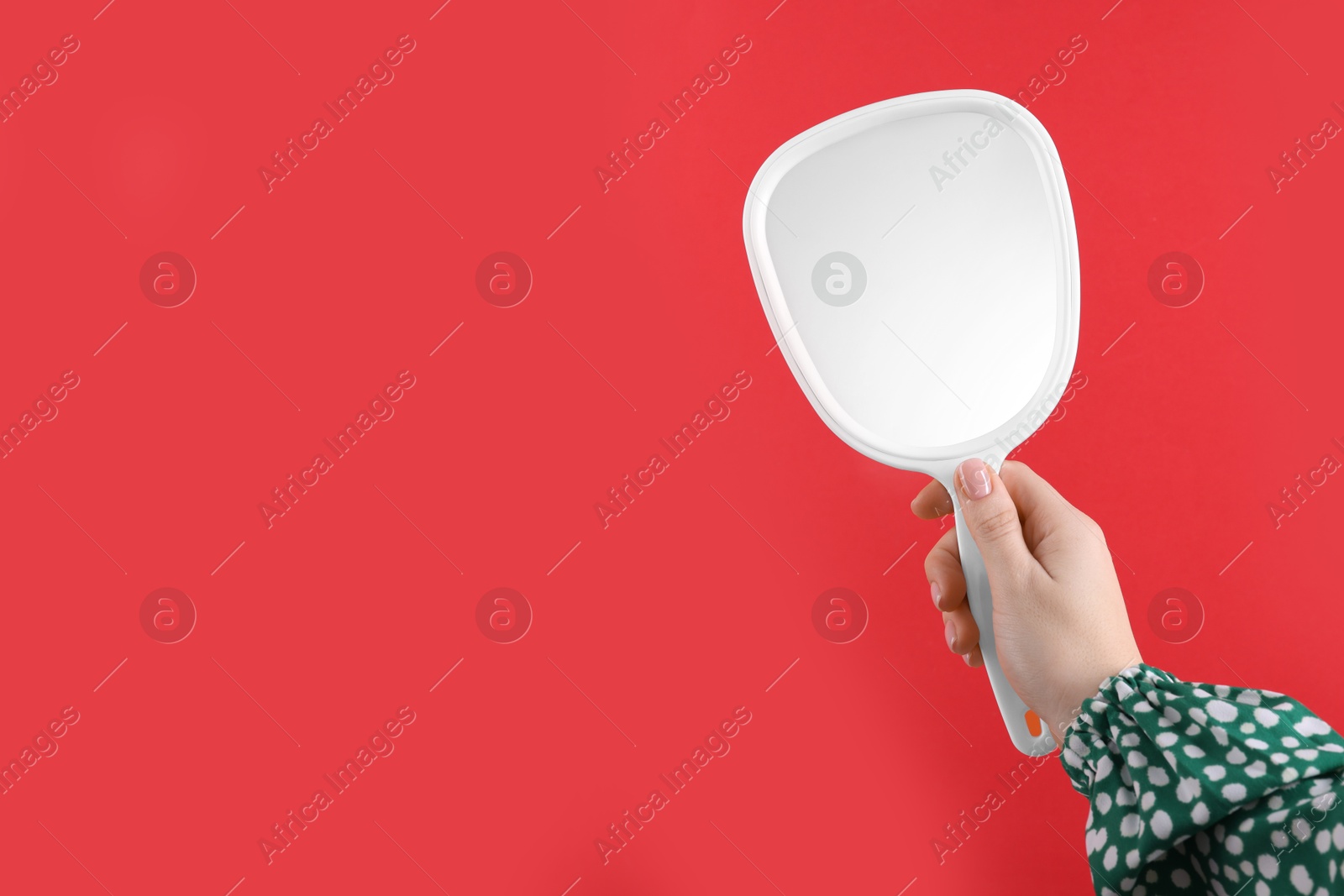 Photo of Woman holding handheld mirror on red background, closeup. Space for text