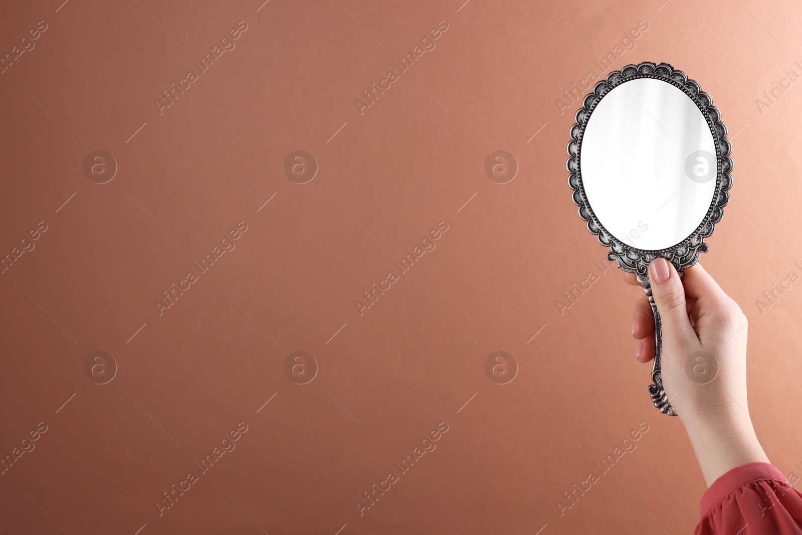 Photo of Woman holding beautiful mirror on beige background, closeup. Space for text