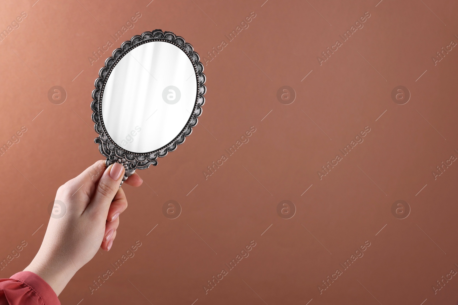 Photo of Woman holding beautiful mirror on beige background, closeup. Space for text