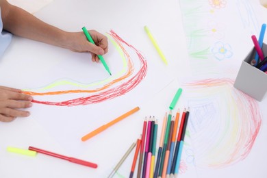 Photo of Boy drawing rainbow at white table, closeup