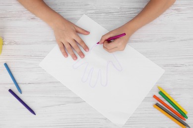 Photo of Boy drawing his palm at light wooden table, top view