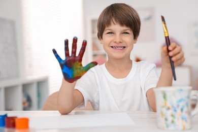 Photo of Happy boy drawing with palm at light table in kindergarten