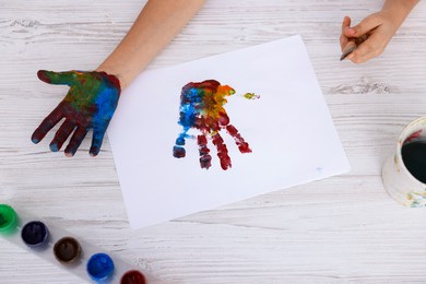 Photo of Boy drawing with palm at light wooden table, top view